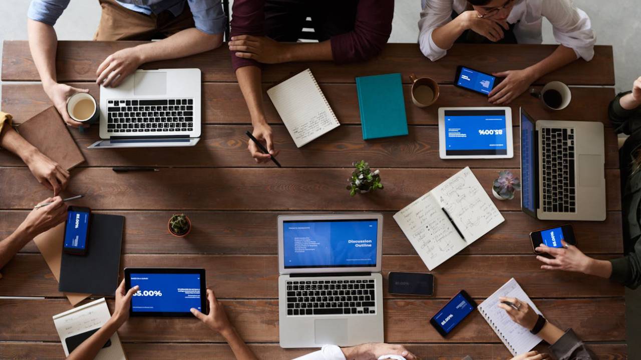 image of a group of people sitting at a desk with their laptops open