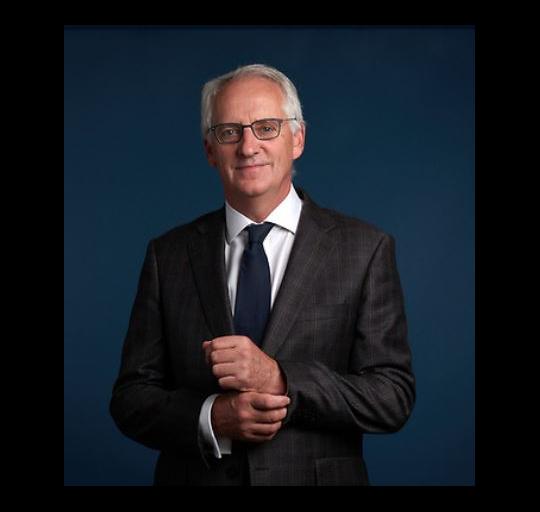  A man in a suit and tie posing for a portrait with a neutral background.
