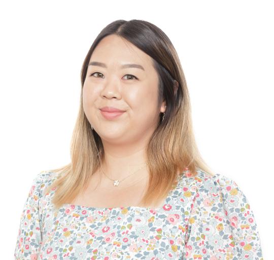  A woman with long hair wearing a floral top, standing gracefully against a light neutral background